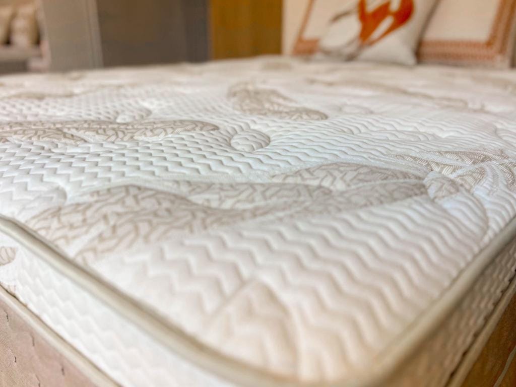 Foco na etiqueta de autenticidade da linha Lisboa costurada na lateral elegante e texturizada do colchão.