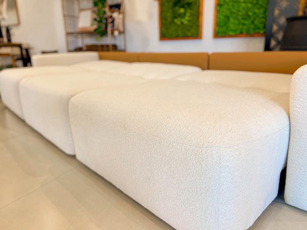 Foco aproximado e detalhado na trama do tecido macio e na precisão milimétrica das costuras do assento do sofá Empíreo.