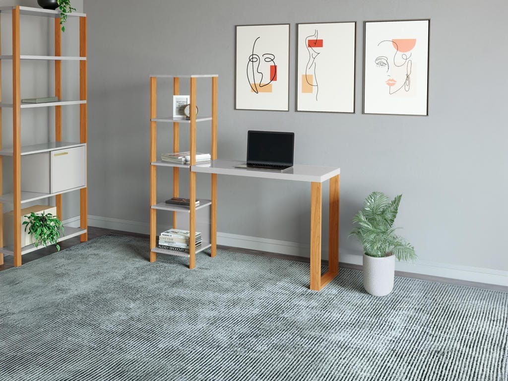 Home office contemporâneo com parede cinza exibindo a Escrivaninha F29 em versão branca clean com pés amadeirados, integrada a uma estante torre com livros e um notebook aberto sobre o tampo.