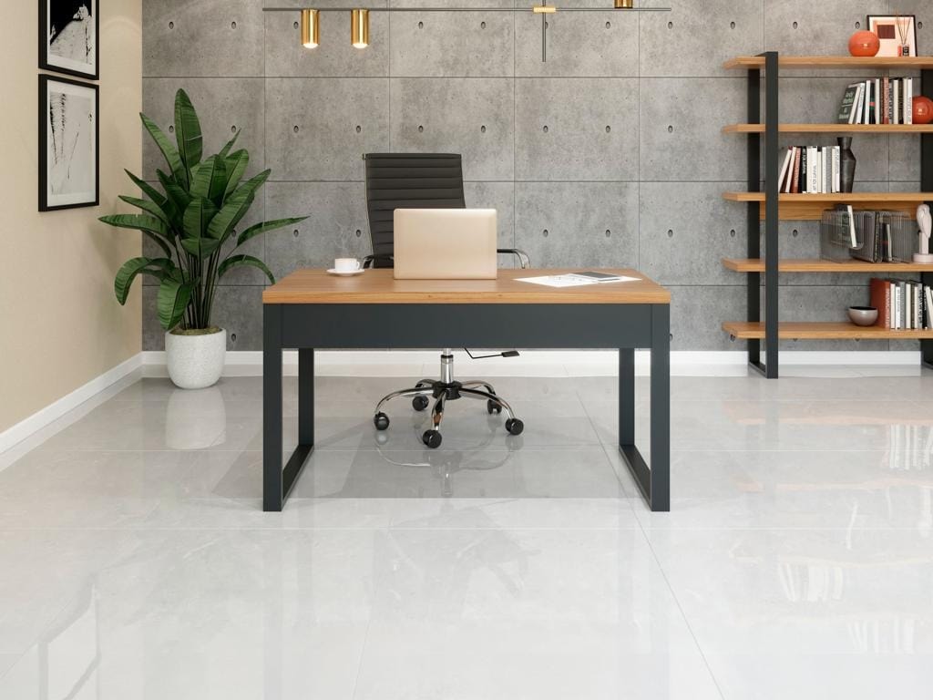 Visão frontal de atendimento da Mesa de Escritório Diretor F20 em MDF amadeirado com base grafite escura, posicionada no centro de uma sala moderna com parede texturizada de concreto.