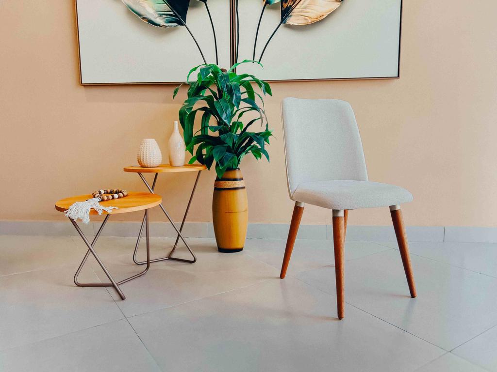 Cadeira estofada bege vista de lado, destacando a inclinação suave do encosto e a estabilidade dos pés.