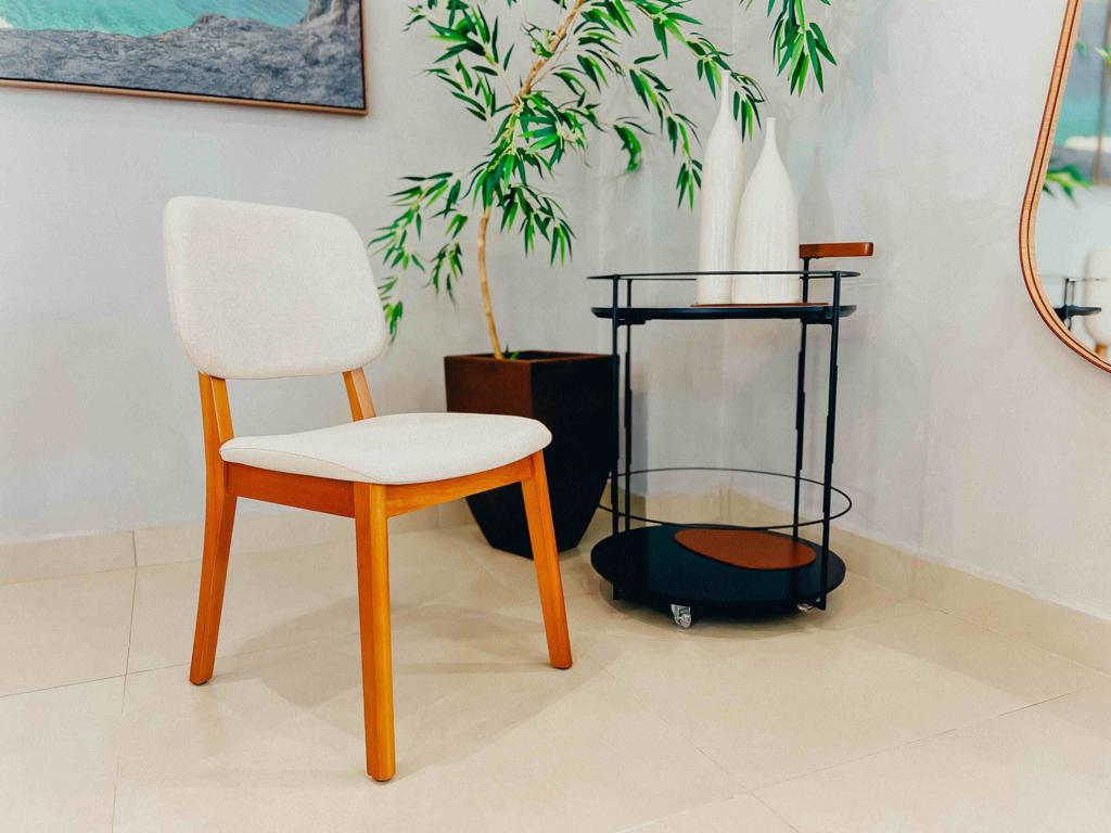 Cadeira Classic estofada posicionada em ângulo em uma sala decorada, ao lado de um vaso marrom e carrinho bar preto.