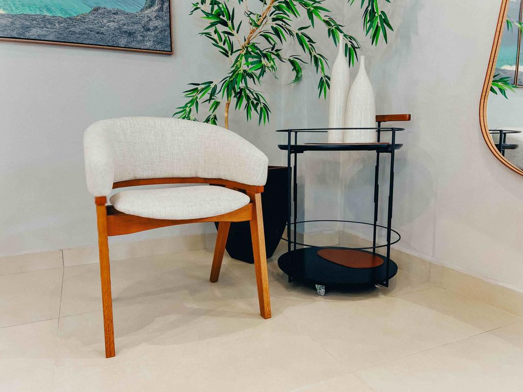 Cadeira Dubai vista frontal em madeira maciça e estofado claro em ambiente decorado.