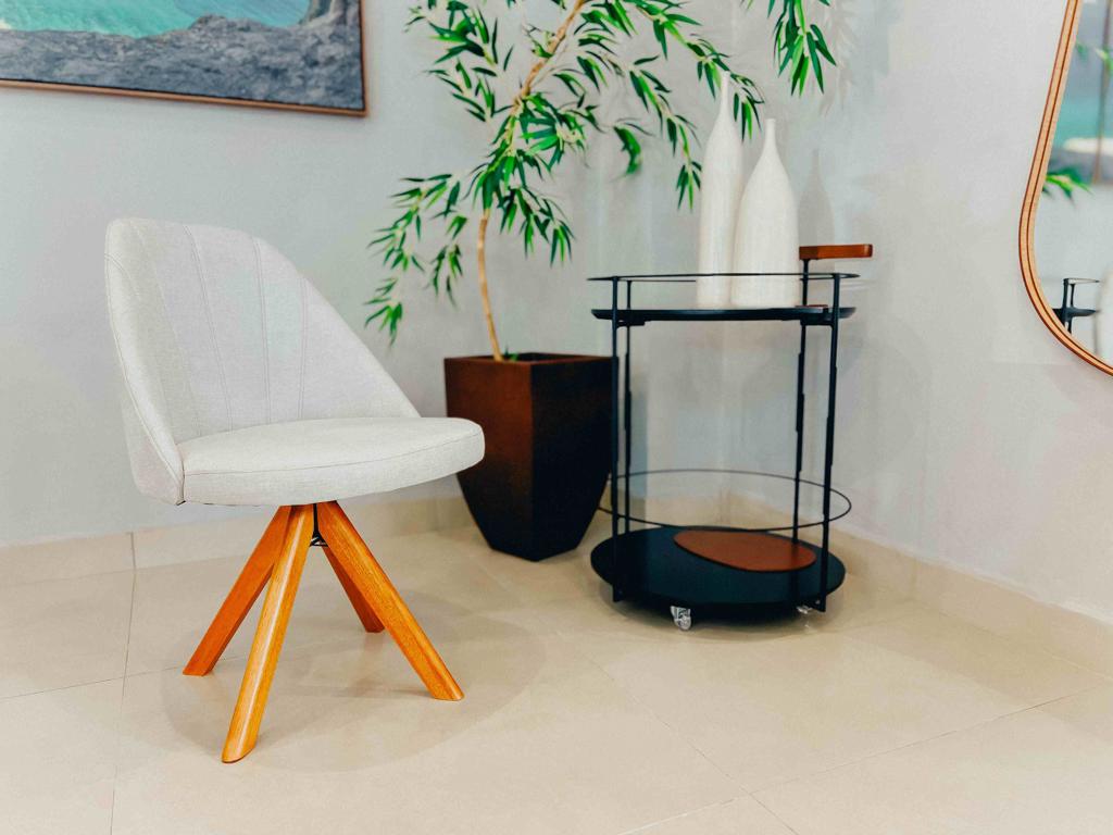 Vista frontal da Cadeira Guns, destacando o encosto curvo com detalhes de costura e pés angulados.