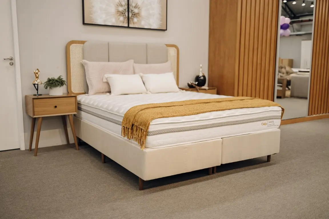 Quarto de casal elegante destacando a cama box Immensity de laterais escuras, arrumada com lençóis claros e travesseiros volumosos.