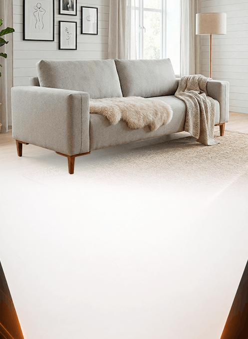 Bright living room with a light gray loveseat, beige throw blanket, and fluffy rug under natural light from a windowed wall; framed art decorates the wall.