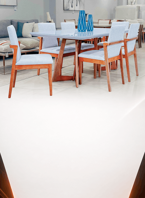 Wooden dining table with light blue upholstered chairs and blue vases on top, in a modern showroom setting