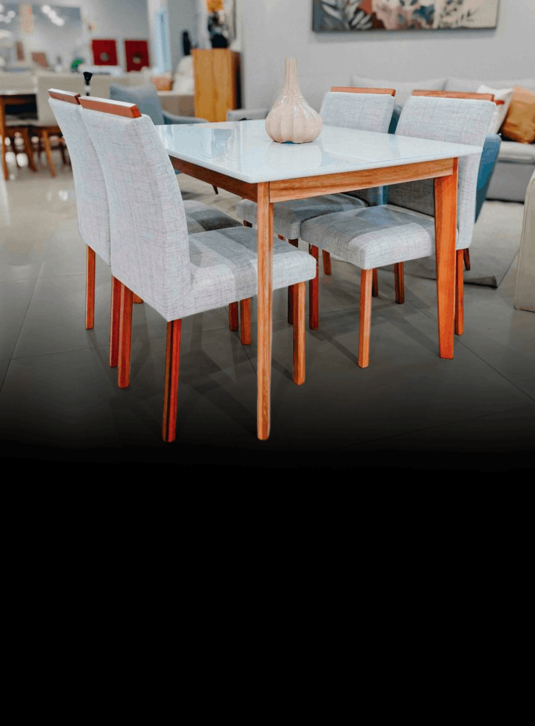 Wooden dining table with six light gray upholstered chairs, and a ceramic vase on the glass-top table in a showroom setting.