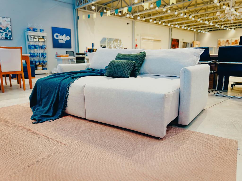 Sofá Cama Cross Moderno Sofá cama cross bege com almofadas verdes em ambiente.