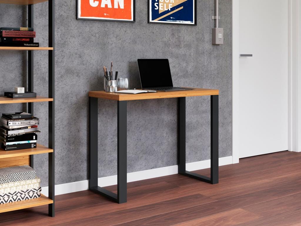 Mesa de Escritório Industrial F11 Compacta | Ciello Escrivaninha compacta F11 amadeirada com pés pretos em estilo industrial, contendo um notebook aberto e caderno sobre o tampo de 38mm, posicionada contra uma parede cinza texturizada.