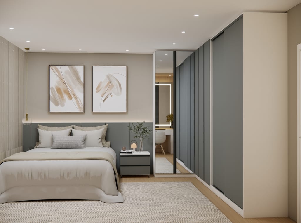 Quarto de casal contemporâneo com mobiliário modulado em formato de L. À direita, um roupeiro espaçoso apresenta portas de correr em tom cinza fosco. No canto do ambiente, destaca-se um módulo com portas revestidas a espelho que reflete o interior do quarto. À esquerda, uma cama de casal com cabeceira estofada cinza e uma mesa de cabeceira com gavetas, sob uma parede decorada com dois quadros abstratos em tons neutros.