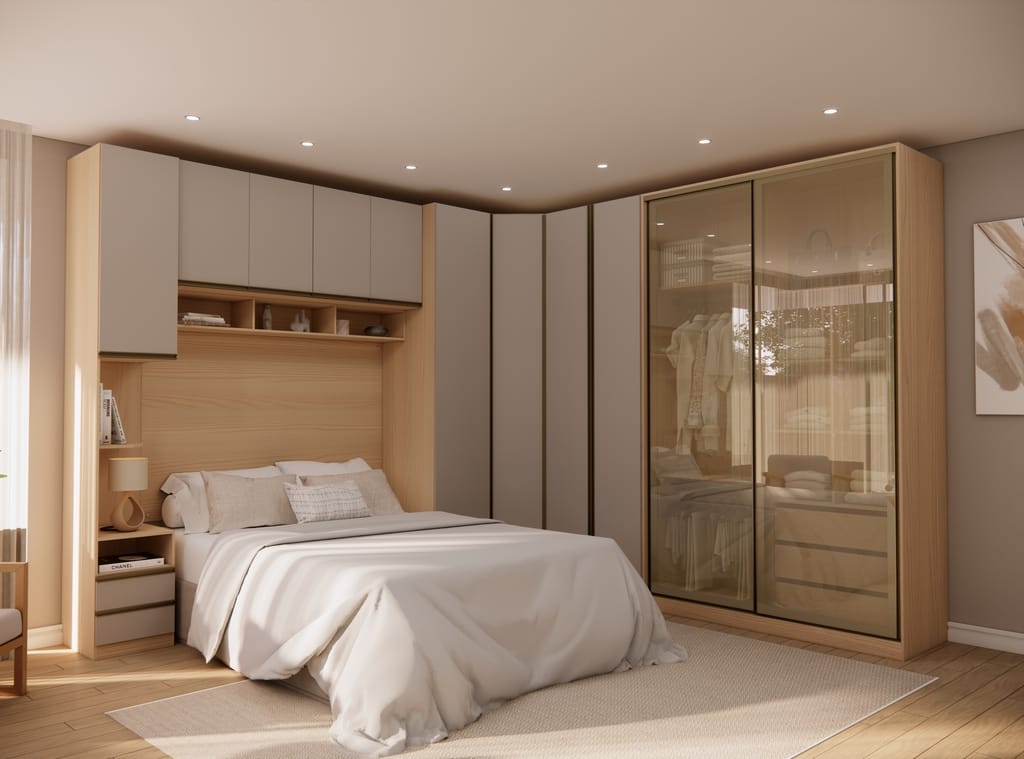 Quarto de casal contemporâneo decorado com móveis modulados em formato de L. O conjunto apresenta uma caixaria amadeirada clara e portas aéreas em tom fendi. À direita, destaca-se um roupeiro com portas de correr em vidro reflecta bronze que revela suavemente o interior. Ao centro, a cama posicionada sob um armário de ponte com nichos abertos iluminados e mesa de cabeceira integrada.